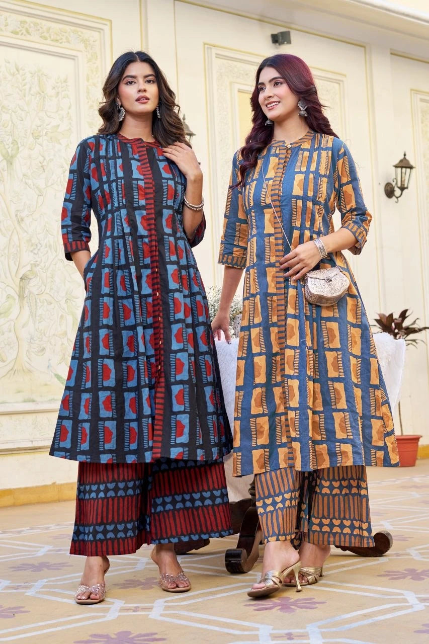 Two women wearing matching patterned outfits in a decorated room.